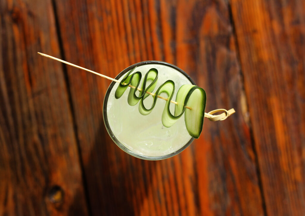 A vibrant cocktail served in a stylish glass, garnished with a slice of citrus and herbs, set against the backdrop of Long Beach's relaxed and inviting atmosphere.
